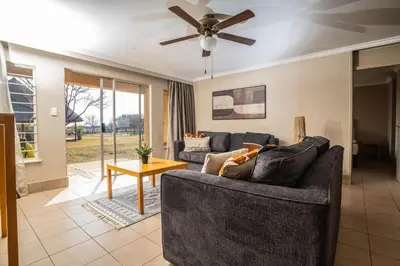 a living room with a couch and a ceiling fan at Carousel Eco Estate in Temba