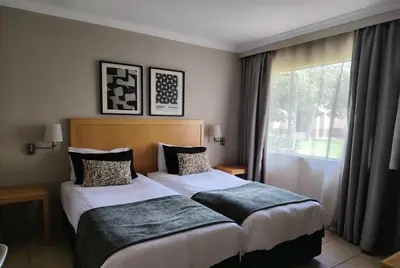 two beds in a hotel room with a window at Carousel Eco Estate in Temba