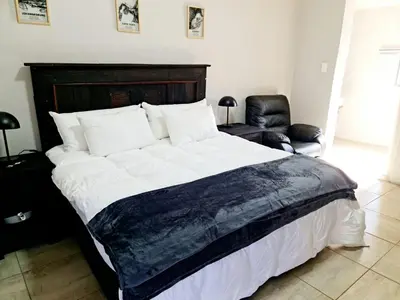 a bedroom with a large bed and a chair at B&B Accommodation 109 Bezuidenhout in Mokopane