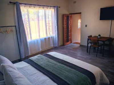 a bedroom with a bed and a table and a desk at African Hoopoe Inn in Polokwane