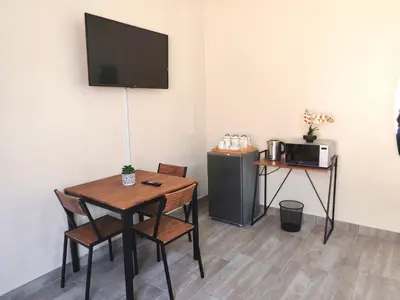 a room with a table and a microwave and a table with chairs at African Hoopoe Inn in Polokwane