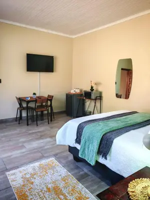 a bedroom with a bed and a table and a television at African Hoopoe Inn in Polokwane