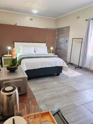 a bedroom with a bed and a table with wine glasses at African Hoopoe Inn in Polokwane