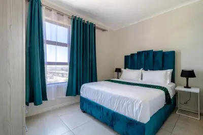 a bedroom with a bed with blue curtains and a window at Golden Sunset Skyline View in Midrand