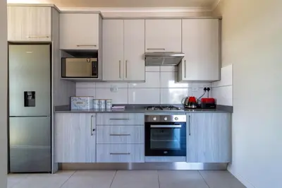 a kitchen with stainless steel appliances and white cabinets at Golden Sunset Skyline View in Midrand