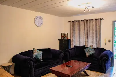 a living room with two couches and a clock on the wall at LOSKOP HOSPITALITY at TOLEDO APARTMENTS in Pretoria
