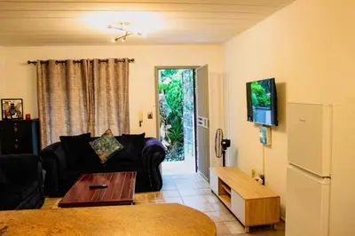 a living room with a couch and a tv at LOSKOP HOSPITALITY at TOLEDO APARTMENTS in Pretoria