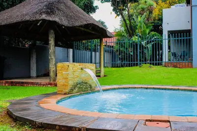 a small pool with a fountain in a yard at LOSKOP HOSPITALITY at TOLEDO APARTMENTS in Pretoria