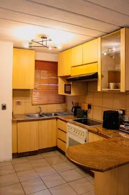 a kitchen with wooden cabinets and a counter top at LOSKOP HOSPITALITY at TOLEDO APARTMENTS in Pretoria