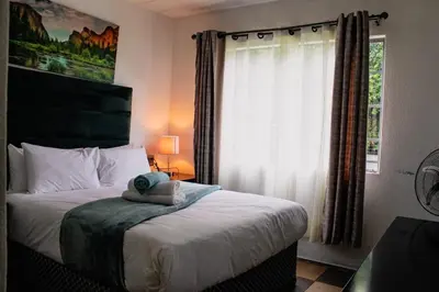 a bedroom with a large bed with a window at LOSKOP HOSPITALITY at TOLEDO APARTMENTS in Pretoria