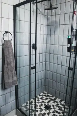 a shower stall with a black and white tiled wall at LOSKOP HOSPITALITY at TOLEDO APARTMENTS in Pretoria