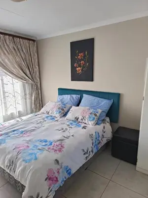 a bedroom with a bed with a blue headboard at Centurion villa in Centurion