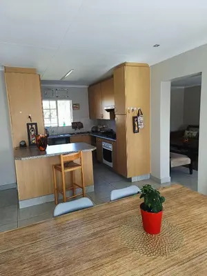 a kitchen with wooden cabinets and a table with a potted plant at Centurion villa in Centurion