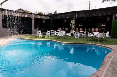 a swimming pool with chairs and a table in the background at Empfunweni Guesthouse in Matsulu