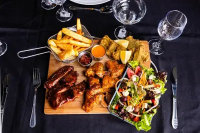 a plate of food with meat and a salad and french fries at Empfunweni Guesthouse in Matsulu