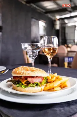 a sandwich and french fries on a plate with wine glasses at Empfunweni Guesthouse in Matsulu