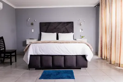 a bedroom with a large bed and a blue rug at Empfunweni Guesthouse in Matsulu