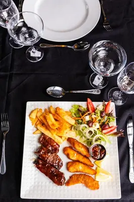 a plate of food with meat and french fries on a table at Empfunweni Guesthouse in Matsulu