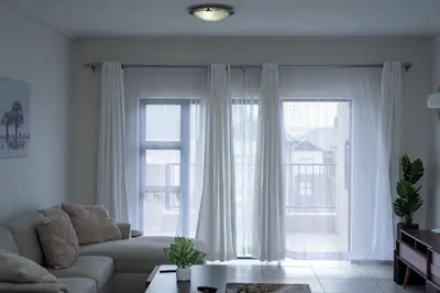 a living room with a couch and two large windows at Homeaway in Midrand