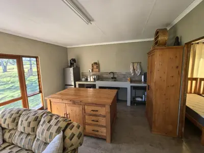 a living room with a couch and a kitchen at Klugro Cottage in Nelspruit