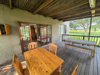 a wooden table and chairs on a wooden deck at Klugro Cottage in Nelspruit