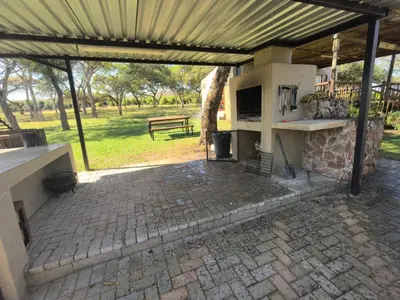 an outdoor patio with a fireplace and a bench at Klugro Cottage in Nelspruit