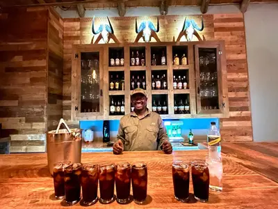 a man standing behind a bar with a row of glasses at RoiSan Private Game Lodge in Rooiberg