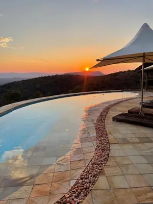 a swimming pool with a sunset in the background at RoiSan Private Game Lodge in Rooiberg