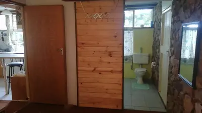 a bathroom with a toilet and a wooden door at Cottage of the Grumpy Old Man, no loadshedding in Pretoria