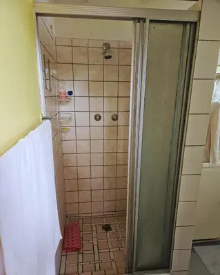 a bathroom with a shower with a glass door at Cottage of the Grumpy Old Man, no loadshedding in Pretoria