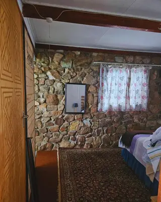 a room with a stone wall with a bed and a television at Cottage of the Grumpy Old Man, no loadshedding in Pretoria