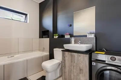 a bathroom with a toilet sink and a washing machine at Lowveld Getaway in Nelspruit