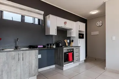 a kitchen with white cabinets and a stove top oven at Lowveld Getaway in Nelspruit