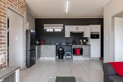 a kitchen with white cabinets and a black wall at Lowveld Getaway in Nelspruit