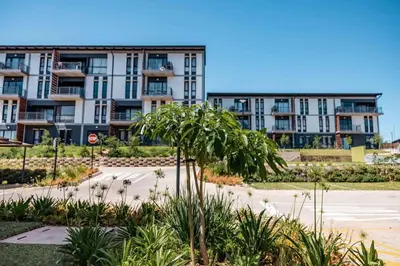 an apartment building with a palm tree in front of a parking lot at Lowveld Getaway in Nelspruit