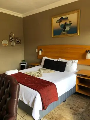 a bedroom with a large bed and a chair at Urban Space Lodge in Pretoria