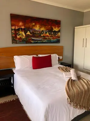 a bedroom with a white bed with a red pillow at Urban Space Lodge in Pretoria