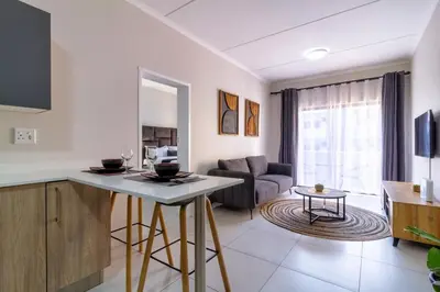 a kitchen and living room with a couch and a table at First Floor 2 Beds Premium Suite in Midrand