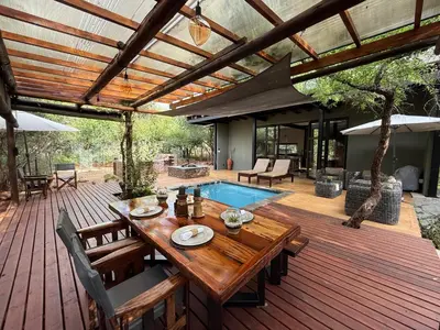 a wooden deck with a table and a swimming pool at Sunset Bush Retreat & Safari's in Marloth Park