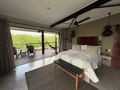 a bedroom with a large bed and a balcony at Sunset Bush Retreat & Safari's in Marloth Park