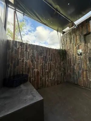 a room with a stone wall next to a table at Sunset Bush Retreat & Safari's in Marloth Park