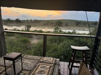 a balcony with two stools and a view of a field at Sunset Bush Retreat & Safari's in Marloth Park