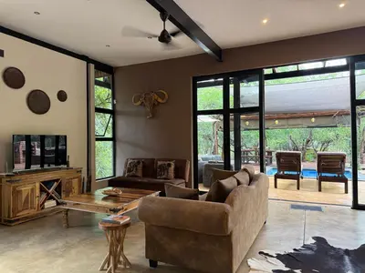 a living room with a couch and a table at Sunset Bush Retreat & Safari's in Marloth Park