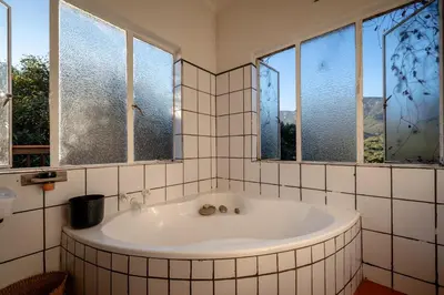 a bath tub in a bathroom with two windows at 59 Kiepersol in Kampersrus AH