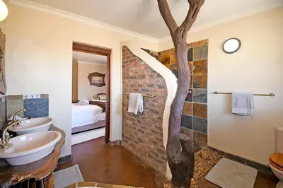 a bathroom with a sink and a tree in it at Damani Lodge at Zebula Golf Estate and Spa in Warmbaths