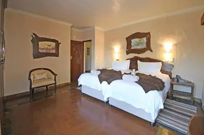 a bedroom with two beds and two chairs at Damani Lodge at Zebula Golf Estate and Spa in Warmbaths