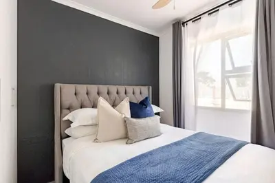 a bedroom with a bed with blue and white pillows at Amani Place Midrand in Midrand
