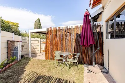 a patio with a table and chairs and a fence at Amani Place Midrand in Midrand