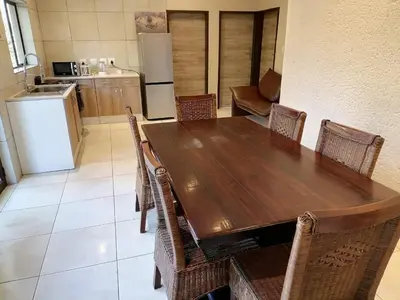 a kitchen with a wooden table with chairs and a refrigerator at Lion and Cheetah Sanctuary in Cullinan