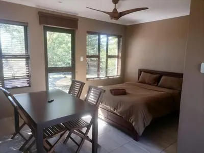 a bedroom with a bed and a table and chairs at Lion and Cheetah Sanctuary in Cullinan